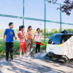 Idriverplus WOXIAOBAI, equipped with two Velodyne Puck sensors, safely navigates and cleans streets in China with children looking on