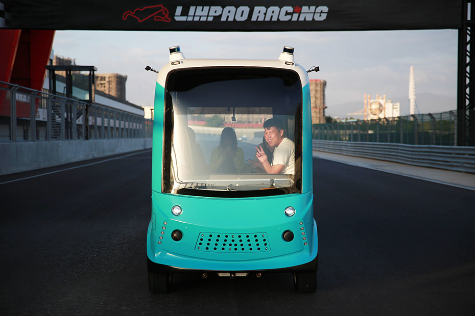 TURING Drive's 4-meter OPAL Shuttle With Velodyne Puck lidar sensors driving on a racetrack with passengers